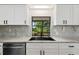 The white kitchen features stainless steel appliances, dark fixtures, and backyard views at 27477 Old Trilby Rd, Brooksville, FL 34602