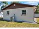 Back exterior of a stucco home with brown trim, two windows, and an air conditioning unit at 2873 Karen Ave, Largo, FL 33774