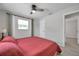 Cozy bedroom with a red quilt, tile floors, and a ceiling fan, leading to an ensuite bathroom for convenience at 2873 Karen Ave, Largo, FL 33774