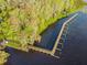 Stunning aerial view of a long wooden pier extending into a calm lake surrounded by lush greenery at 2919 Northfield Dr, Tarpon Springs, FL 34688