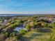 Scenic aerial view of the community park's sports fields and courts surrounded by lush green trees and a serene lake in the distance at 2919 Northfield Dr, Tarpon Springs, FL 34688