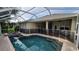 A screened in pool and spa feature a safety fence and brick paver surround in this backyard at 2919 Northfield Dr, Tarpon Springs, FL 34688