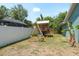Backyard featuring a ' playset, fully fenced yard, and tropical landscaping for outdoor enjoyment at 3647 Scarlet Tanager Dr, Palm Harbor, FL 34683