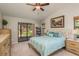 Bright bedroom features a ceiling fan, sliding glass doors to the yard, and a cozy bed with stylish blue accents at 3647 Scarlet Tanager Dr, Palm Harbor, FL 34683