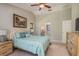 Bright bedroom features a ceiling fan, vaulted ceilings, and a cozy bed with stylish blue accents at 3647 Scarlet Tanager Dr, Palm Harbor, FL 34683