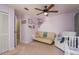 Bedroom featuring a futon, comfortable armchair, ceiling fan, and peaceful purple color scheme at 3647 Scarlet Tanager Dr, Palm Harbor, FL 34683