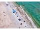An expansive beachside view showcases white sand, clear turquoise water, and vibrant beachgoers enjoying a sunny day at 400 150Th Ave # 506, Madeira Beach, FL 33708