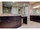Bathroom featuring dark cabinets, granite countertops, undermount sinks, large mirror, and decorative lighting at 4975 Night Star Trl, Odessa, FL 33556