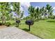 Community grilling area featuring two black grills, stone flooring, and green lawn at 4975 Night Star Trl, Odessa, FL 33556