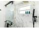 Shower featuring a sliding glass door, marble tile, a window, and sleek black hardware at 512 Flamingo Dr, Apollo Beach, FL 33572