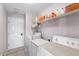 Laundry room with washer, dryer, freezer, storage shelves, and white door, providing convenience and functionality at 6607 Gates Pointe Way, Riverview, FL 33578