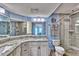 Bright bathroom with white cabinets, granite countertops, large mirror, and glass shower at 7480 Bayshore Dr # 402, Treasure Island, FL 33706