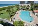 Aerial view of a sparkling blue pool surrounded by palm trees and lounge chairs near the beach at 7480 Bayshore Dr # 402, Treasure Island, FL 33706