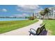 Exterior view of community manicured grounds with paved walkway, benches, blue skies, water view, and condo building at 7872 Sailboat Key S Blvd # 306, South Pasadena, FL 33707