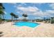 Community outdoor pool with light brick surround, palm trees, lounge chairs, and beautiful blue sky view at 7872 Sailboat Key S Blvd # 306, South Pasadena, FL 33707