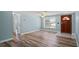 Bright living room with wood-look floors, neutral paint, and welcoming front door at 8317 Needles Dr, Hudson, FL 34667