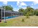 A screened-in pool provides a private oasis in the backyard of this property, surrounded by lush greenery and a blue sky backdrop at 8317 Needles Dr, Hudson, FL 34667