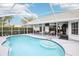 Outdoor seating, ceiling fans and a television look onto a large in-ground pool at this home at 8804 Poe Dr, Hudson, FL 34667