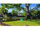 Secluded backyard with lake view featuring mature trees, lush lawn and a relaxing Adirondack chair at 9072 Baywood Park Dr, Seminole, FL 33777