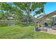 Water view from a backyard patio with comfortable seating under a large shade tree at 9072 Baywood Park Dr, Seminole, FL 33777