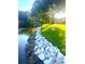 Backyard featuring waterfront landscaping, native plants, and a rock border along the shoreline at 9072 Baywood Park Dr, Seminole, FL 33777