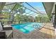 Sparkling pool with a screened-in enclosure with a water view and comfortable lounge chairs at 9072 Baywood Park Dr, Seminole, FL 33777