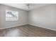 Clean and bright bedroom showcasing wood-look flooring, a ceiling fan, and a large window at 942 Capri Isles Blvd # 207, Venice, FL 34292