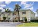 Exterior view of a two story condo complex with yellow siding, white trim and lush landscaping at 942 Capri Isles Blvd # 207, Venice, FL 34292