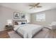 Staged main bedroom with ceiling fan, hardwood floors, neutral colors, and a bright window at 942 Capri Isles Blvd # 207, Venice, FL 34292