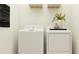 Bright laundry room featuring modern washer and dryer, overhead storage, and minimalist decor at 9645 Runaway Breeze Dr, Land O Lakes, FL 34637