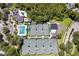 Aerial view highlighting tennis courts, a pool, and clubhouse with lush greenery surrounding the community at 10141 Deercliff Dr, Tampa, FL 33647