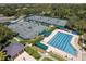 Aerial view featuring a pool, tennis courts, and verdant green trees in a resort style community at 10141 Deercliff Dr, Tampa, FL 33647