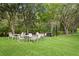 Outdoor picnic area featuring white tables and chairs set up on a green lawn, surrounded by lush trees and string lights at 10141 Deercliff Dr, Tampa, FL 33647