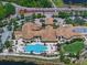 Aerial view of a luxurious clubhouse with a pool, putting green, and lush landscaping in a gated community at 1112 Jasmine Creek Ct, Sun City Center, FL 33573