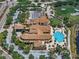 Aerial shot of a community clubhouse with a pool, manicured grounds, ample parking, and a grand entrance at 1112 Jasmine Creek Ct, Sun City Center, FL 33573