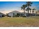 Expansive backyard featuring mature palm trees, a well-maintained lawn, and a screened-in lanai at 1112 Jasmine Creek Ct, Sun City Center, FL 33573