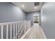 Upstairs hallway featuring plush carpeting, modern lighting, neutral paint and white banister at 11442 Crowned Sparrow Ln, Tampa, FL 33626