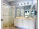 Clean bathroom with glass-enclosed shower, a wide mirror, bright lighting, and neutral vanity at 11457 Captiva Kay Dr, Riverview, FL 33569
