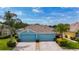 Charming exterior of a blue home featuring a two-car garage, well-manicured landscaping, and mature palm trees at 11457 Captiva Kay Dr, Riverview, FL 33569