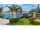 Beautifully landscaped front exterior of a blue home featuring mature palm trees and vibrant shrubbery at 11457 Captiva Kay Dr, Riverview, FL 33569