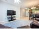 Bright living room with large-screen television, sleek console, and open layout leading into the kitchen and dining area at 11457 Captiva Kay Dr, Riverview, FL 33569