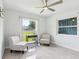 Bright bedroom featuring two chairs, gray tile floor, large windows, and modern ceiling fan at 1226 Debuel Rd, Lutz, FL 33549