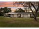 Charming single-story home featuring a well-manicured lawn and a classic brick facade at sunset at 1226 Debuel Rd, Lutz, FL 33549