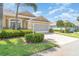 Beautiful home featuring lush green grass, landscaping and a brick paver driveway leading to the attached garage at 1231 Corinth Greens Dr, Sun City Center, FL 33573