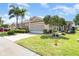 A cozy single-story home with a screened garage, lush landscaping, and a brick paver driveway at 1231 Corinth Greens Dr, Sun City Center, FL 33573