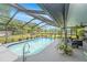 Backyard swimming pool surrounded by a screened-in patio, lush landscaping, and comfortable seating at 12317 Smokey Dr, Hudson, FL 34669