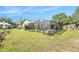 Backyard view of the screened-in pool, surrounded by lush plants and an expansive lawn at 12317 Smokey Dr, Hudson, FL 34669