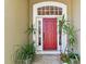 Inviting red front door framed by lush greenery and decorative plants in wicker baskets at 1816 Curry Rd, Lutz, FL 33549