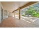 Covered patio featuring tiled floors with view of the blue-tiled pool and nature from the screened-in enclosure at 1816 Curry Rd, Lutz, FL 33549