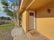 Charming front entrance with a 'hello' mat, yellow siding, and well-maintained landscaping at 2600 N Paula Dr # 2B, Dunedin, FL 34698